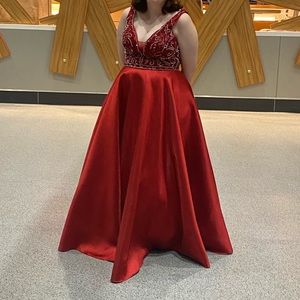 Size 16-18 long red prom dress with beading on the bodice and large pockets.